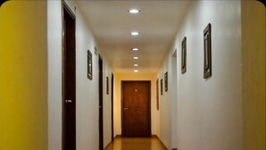 A long, narrow hallway with wooden doors and framed pictures on the walls. - Hotel Villa del Sol (Villa Gesell)