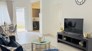 A living room with a sofa, TV, and a dining area with chairs.