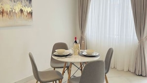 A dining area with a round table, four chairs, and a painting on the wall.
