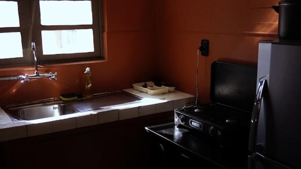 Una cucina compatta con lavello, fornello e frigorifero.