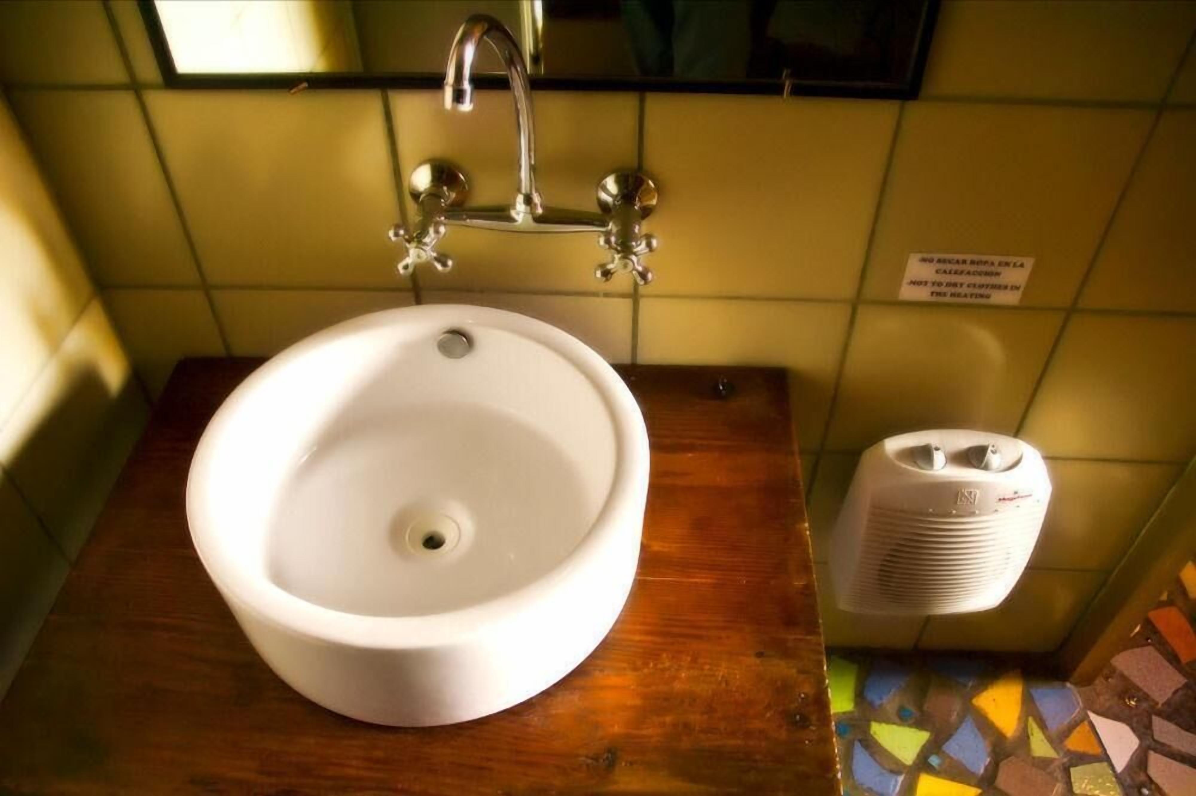 Une salle de bain avec un lavabo blanc, un miroir et un radiateur.