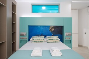 Een moderne slaapkamer met een groot bed, turquoise accentmuren, dakraam en een inbouwkast.