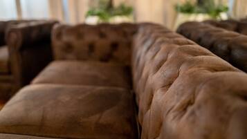 A close-up of a brown leather sofa with a tufted backrest.