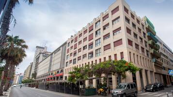 A multi-story hotel with a modern facade, a covered outdoor seating area, and a parking lot.