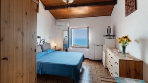 A bedroom with a bed, dresser, window, and a view of the sea. - Holiday Home 'Basera' with Sea View, Wi-Fi & Air Conditioning (Cipressa)