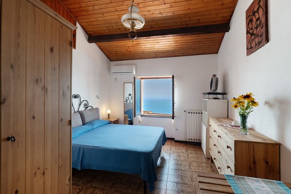 A bedroom with a bed, dresser, window, and a view of the sea. - Holiday Home 'Basera' with Sea View, Wi-Fi & Air Conditioning (Cipressa)