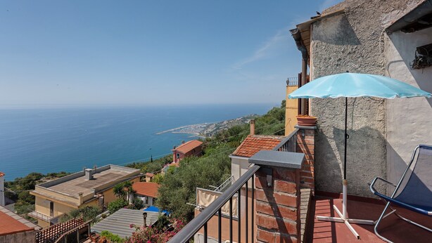 A balcony with a blue umbrella, a chair, and a view of the sea. - Holiday Home 'Basera' with Sea View, Wi-Fi & Air Conditioning (Cipressa)