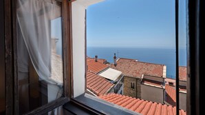 A window with a view of terracotta rooftops and the sea. - Holiday Home 'Basera' with Sea View, Wi-Fi & Air Conditioning (Cipressa)