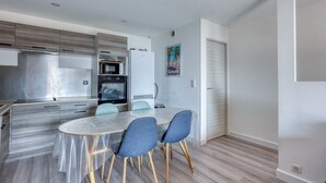 A modern kitchen with stainless steel appliances, a dining table with chairs, and a wooden floor.