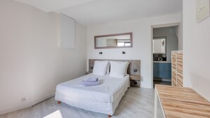 A bedroom with a bed, bedside tables, a mirror, and a wooden bench.