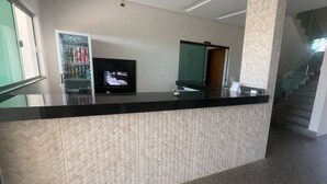 A reception desk with a television, a vending machine, and a glass partition. - Hotel Royal - Rubiataba (Rubiataba)