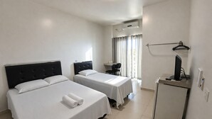 A hotel room with two beds, a desk, a TV, and a small fridge. - Hotel Royal - Rubiataba (Rubiataba)