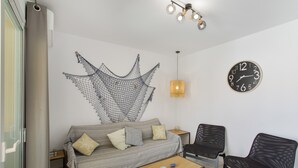 Ein Wohnzimmer mit einer Couch, zwei Sesseln, einem Couchtisch, einer Wanduhr und einer hängenden Netzdekoration.