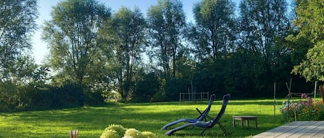 A wooden deck with a picnic table, a metal sculpture, and a potted plant with yellow flowers.