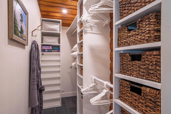 A walk-in closet with shelves and baskets, a hanging rack, and a framed picture on the wall.