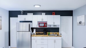 A modern kitchen with white cabinets, a stainless steel refrigerator, a microwave, and a granite countertop.