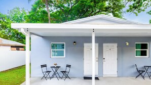 A covered patio with two doors, a small table with chairs, and a window.
