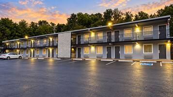 A motel with a two-story structure, multiple rooms, a parking lot, and a decorative wall.