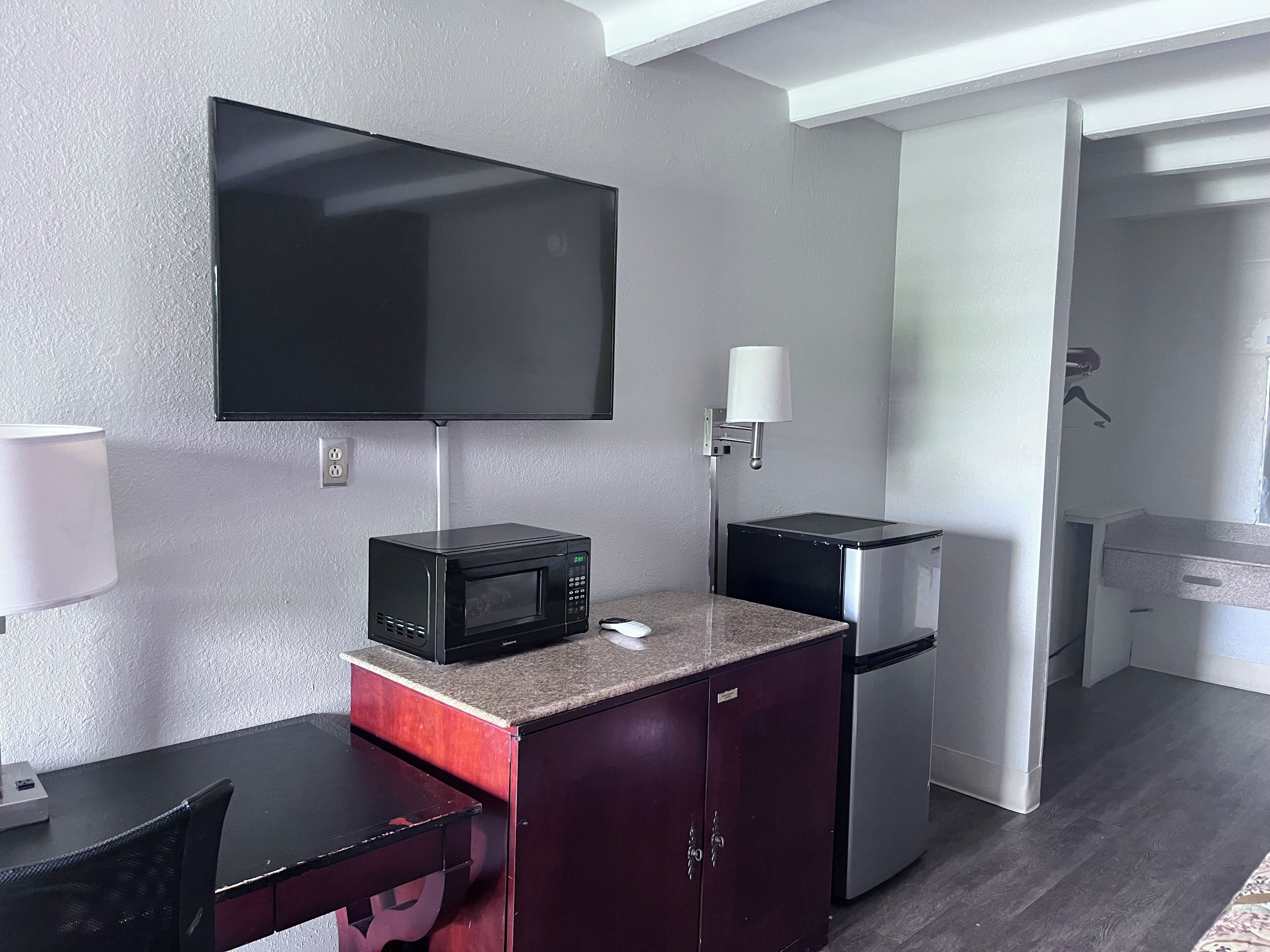 Una kitchenette compacta con microondas, refrigerador y una televisión de pantalla plana montada en la pared.