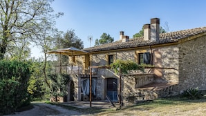 Un edificio de piedra con un balcón, una pérgola y cielo despejado.