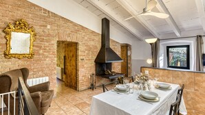 Un comedor con pared de ladrillo, chimenea, una mesa para cuatro y televisor.