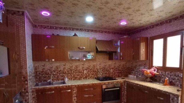 Una cocina con armarios de madera, un lavamanos, una estufa y una ventana.