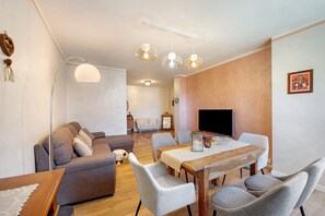 Un salon comprenant un canapé, une table à manger, des chaises et un téléviseur.