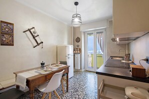 Une cuisine de taille réduite avec un coin repas, un radiateur et une vue sur l’extérieur, visible à travers la porte.