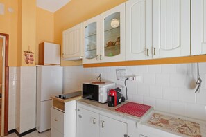 A kitchen with white cabinets, a microwave, a coffee maker, and a red mat on the counter.