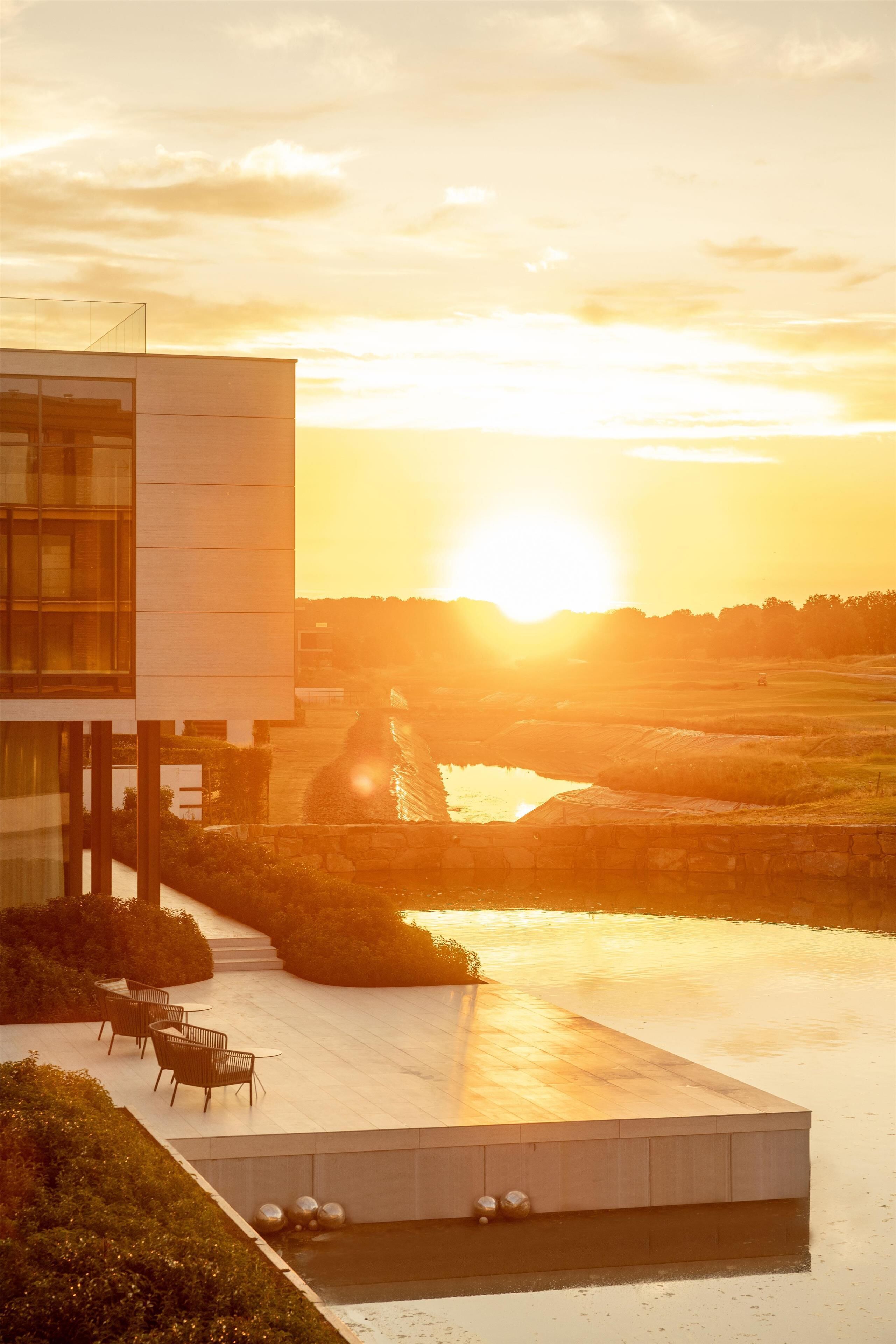 A modern building with a glass facade, a rooftop pool, and outdoor seating.
