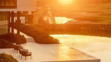 A modern building with a glass facade, a rooftop pool, and outdoor seating.
