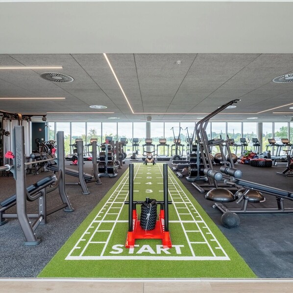 A gym with a starting line, weight machines, treadmills, and a large window. - Radisson Collection The National Hotel, Brussels (Zaventem)