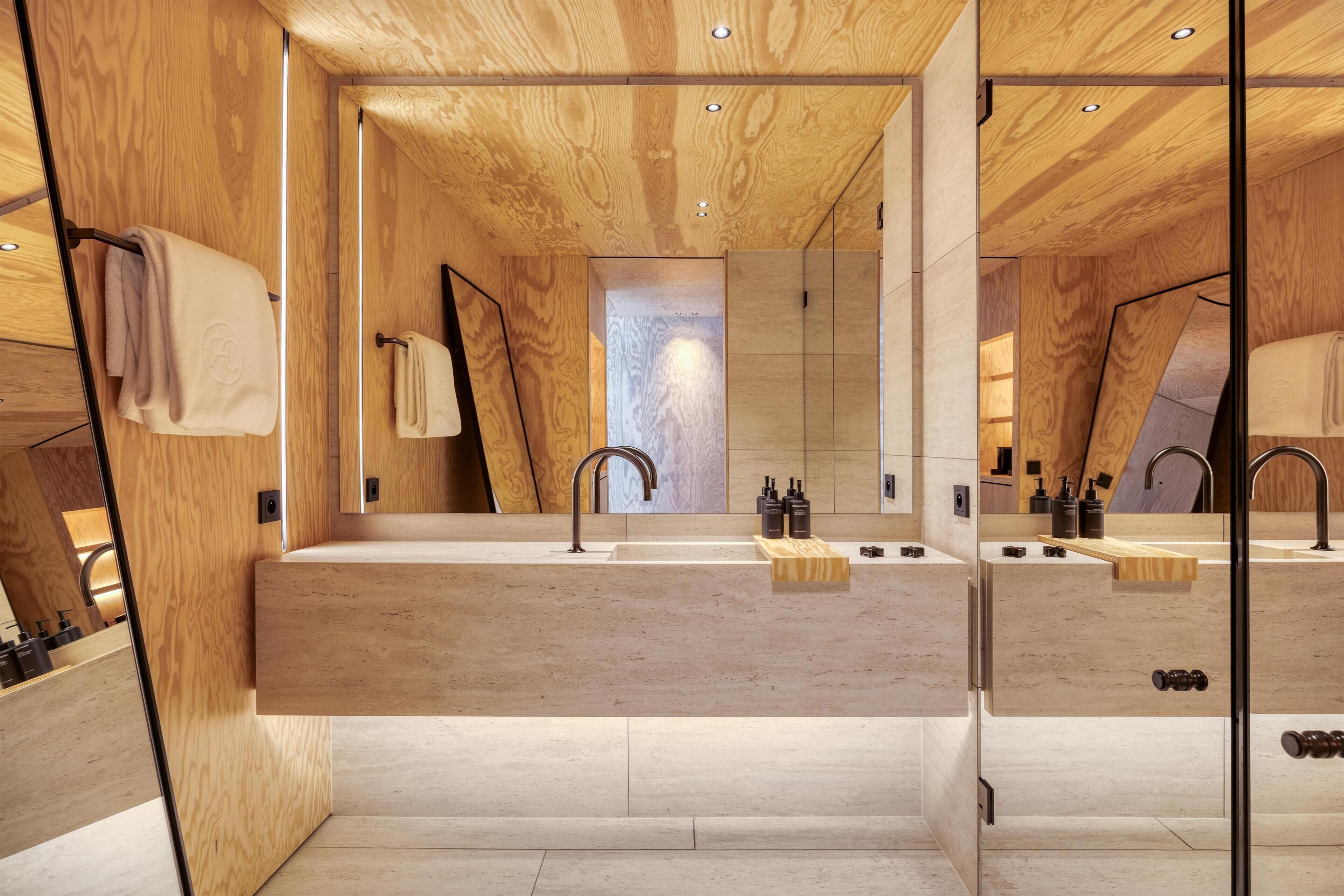 A modern bathroom with a wooden ceiling, a large mirror, and a built-in sink.