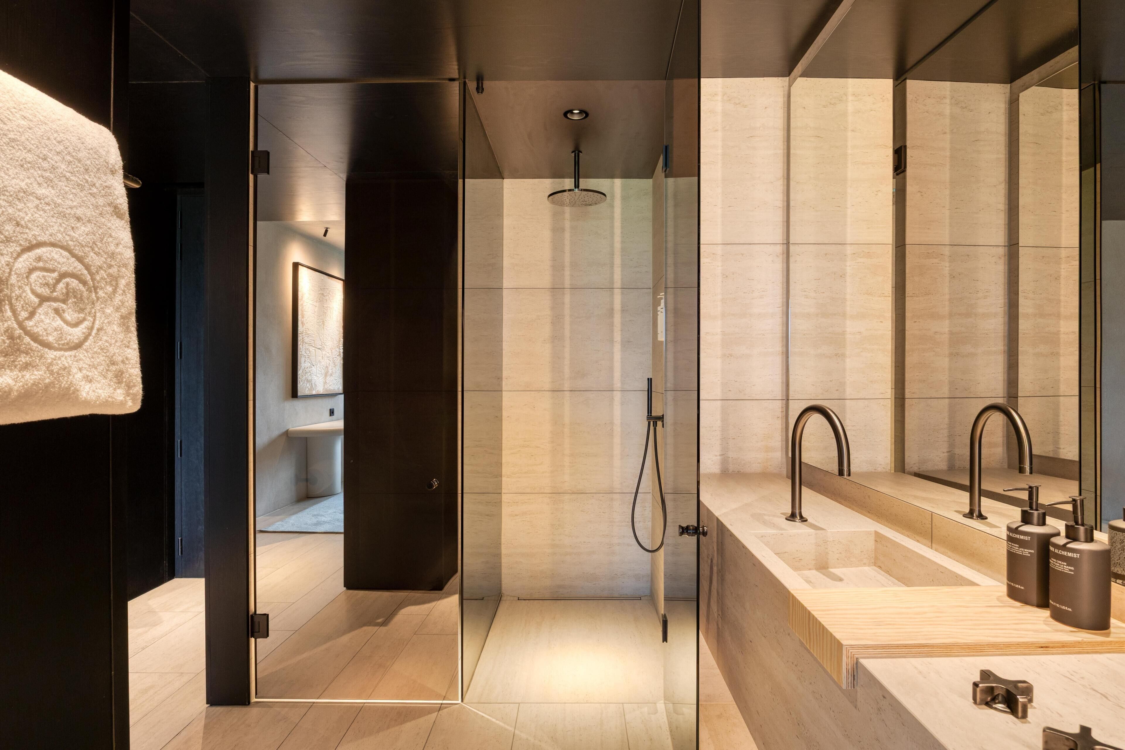 Un baño moderno con cabina de ducha de vidrio, un espejo grande y un mueble de tocador de madera.