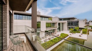 A modern building with a glass balcony, outdoor seating, and a small water feature. - Radisson Collection The National Hotel, Brussels (Zaventem)