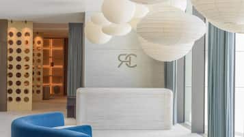 A modern lobby with a seating area, a reception desk, and a decorative ceiling with hanging paper lanterns.