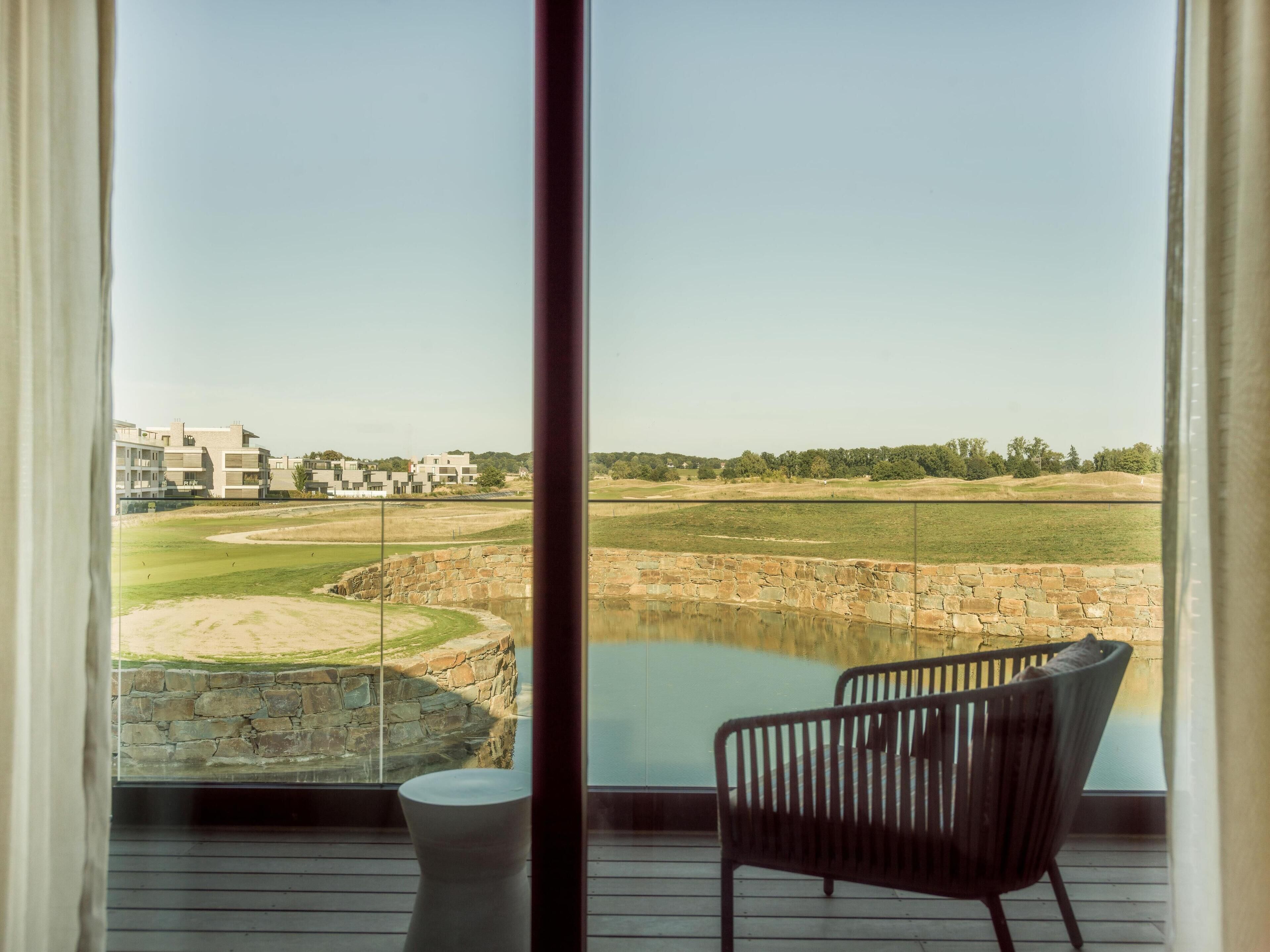 Una habitación moderna con un amplio ventanal con vistas a un campo de golf y una masa de agua.