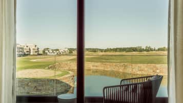 Een moderne kamer met een groot raam met uitzicht op een golfbaan en een waterpartij.