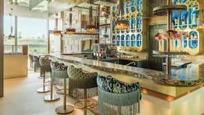 A modern bar area with a marble countertop, bar stools, and a wine display.