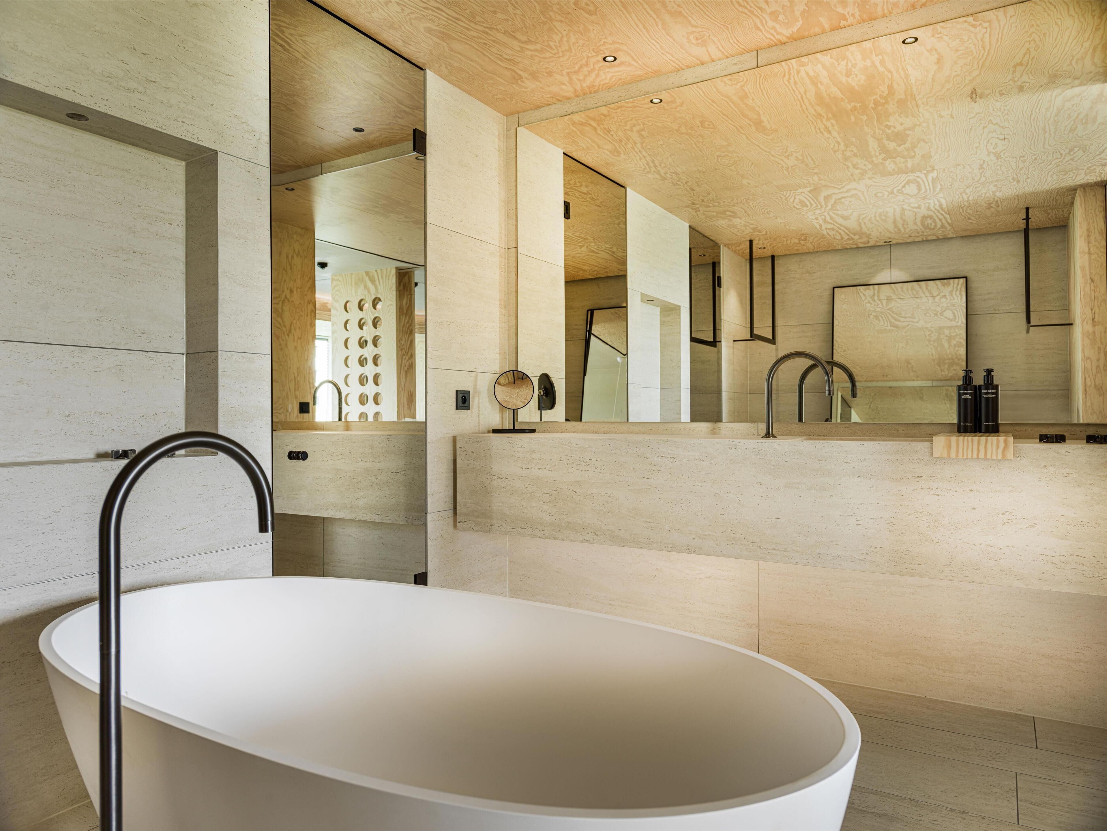 Ein modernes Badezimmer mit einer freistehenden Badewanne, einem großen Spiegel und einem hölzernen Waschtisch.
