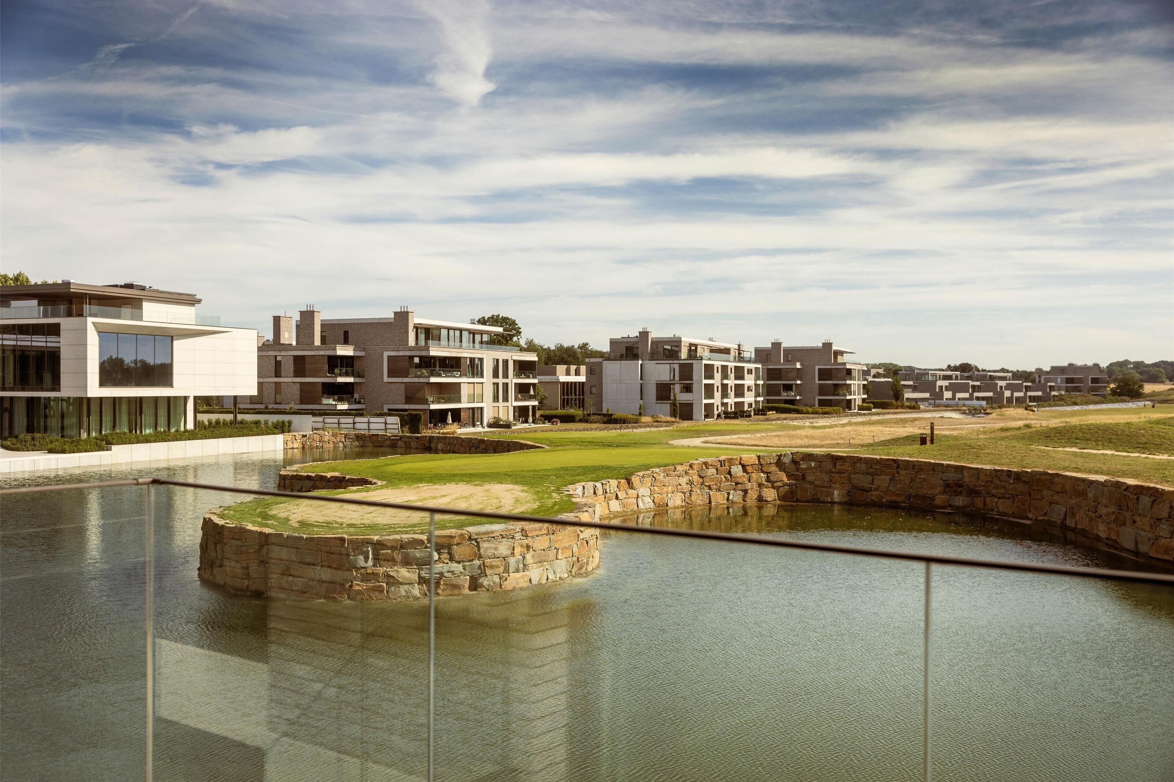 A modern residential area with contemporary architecture, a water feature, and a well-maintained lawn.