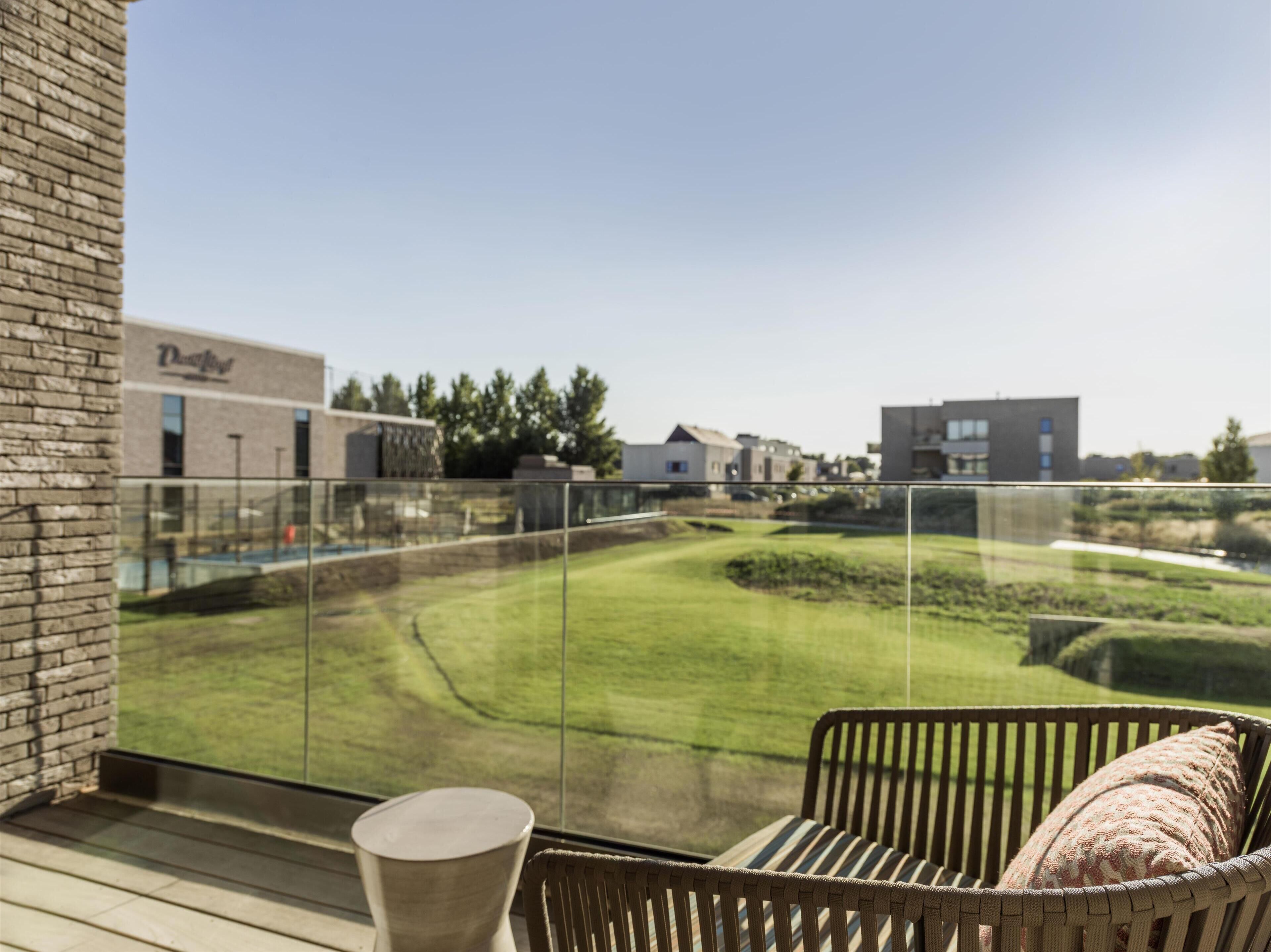 A balcony with a view of a green lawn and buildings in the background.