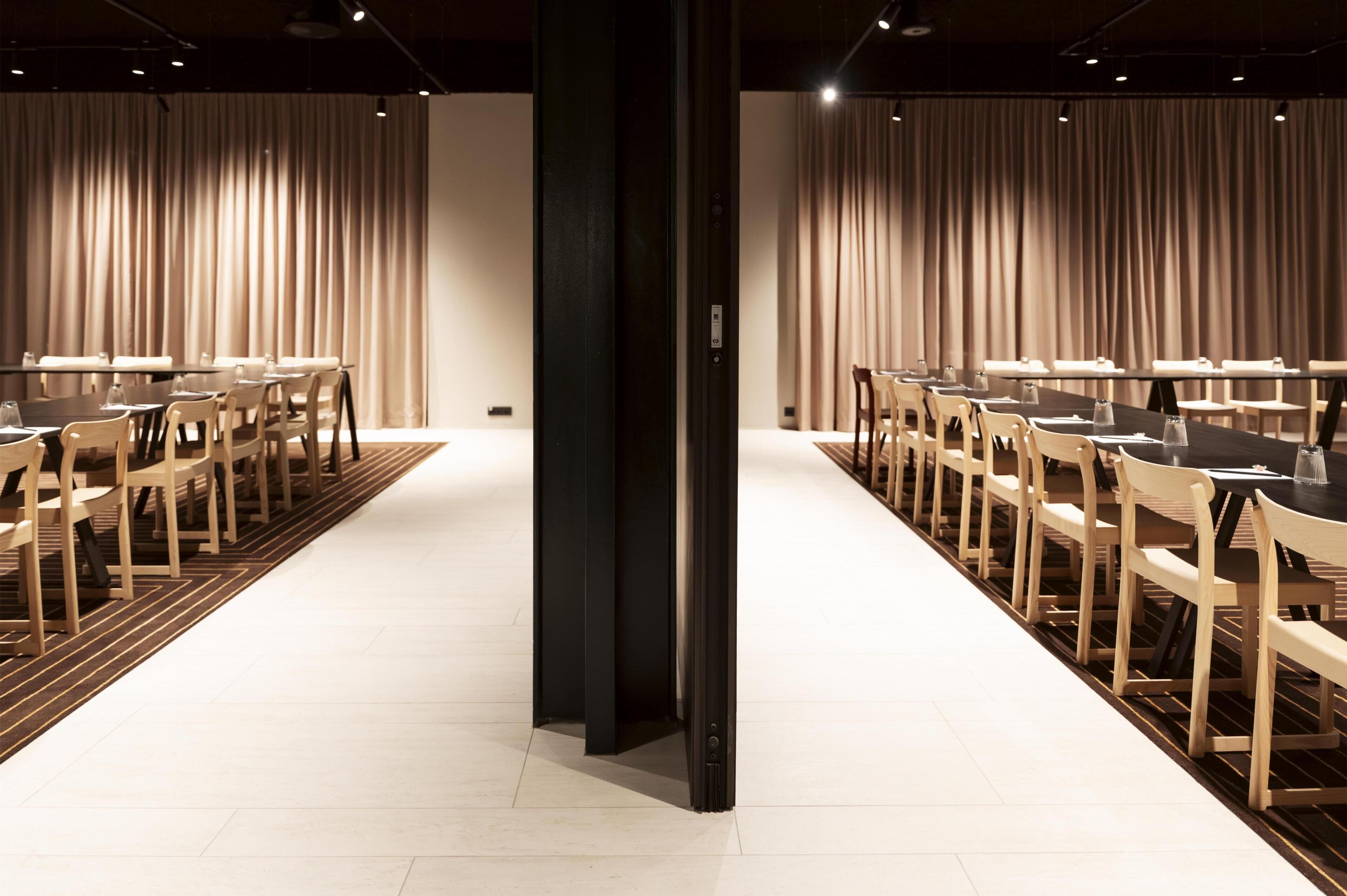 Un salón de conferencias con una larga mesa, sillas y cortinas.