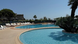A swimming pool with lounge chairs and palm trees. - Studio with direct access to the sea and swimming pool in a green setting (Villeneuve-Loubet)