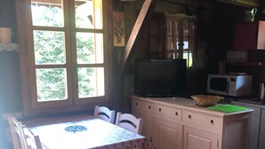 Een landelijke keuken met een houten tafel en stoelen, een magnetron en een televisie.