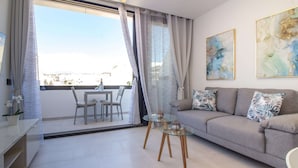 Ein modernes Wohnzimmer mit einer Couch, einem Glastisch und einem Essbereich mit Tisch und Stühlen.