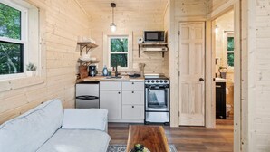 Une cuisine compacte avec des murs en bois, un plan de travail blanc, une cuisinière, un four à micro-ondes et un évier.
