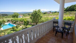A balcony with a view of a vineyard, a swimming pool, and a white building. - Villa with Private Pool, Mountain Views & Wi-Fi in Pantón, Ribeira Sacra (Pantón)