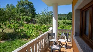 Un balcon avec une table et des chaises, donnant sur un vignoble.