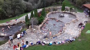 A stone bath surrounded by a stone pathway with people bathing and sitting around. - Villa with Private Pool, Mountain Views & Wi-Fi in Pantón, Ribeira Sacra (Pantón)